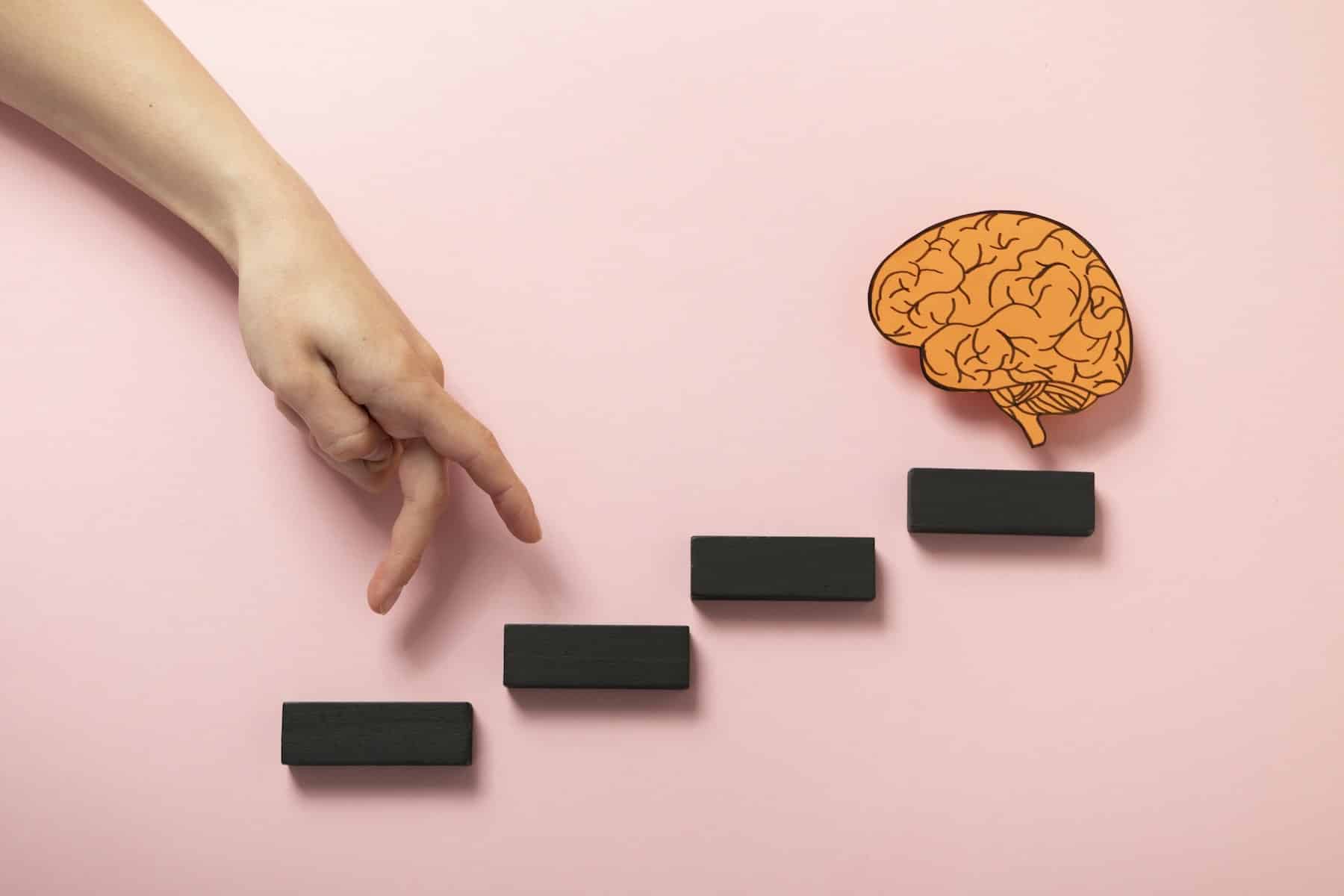 growth mindset significato: grafica con dita che salgono degli scalini immaginari per raggiungere l'immagine di un cervello