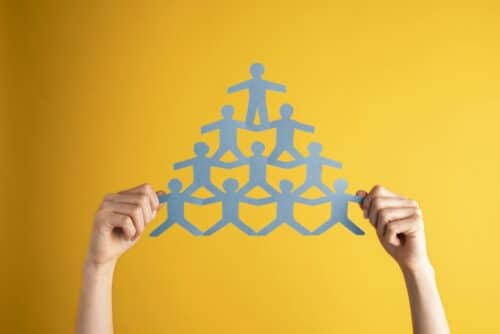 people management: persona che sostiene una piramide di persone fatta in carta