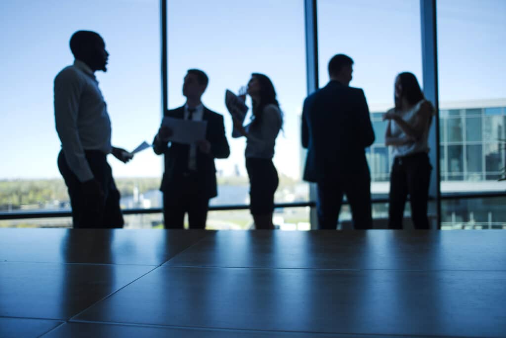 employer branding: profili di persone che chiacchierano in ufficio davanti a una vetrata