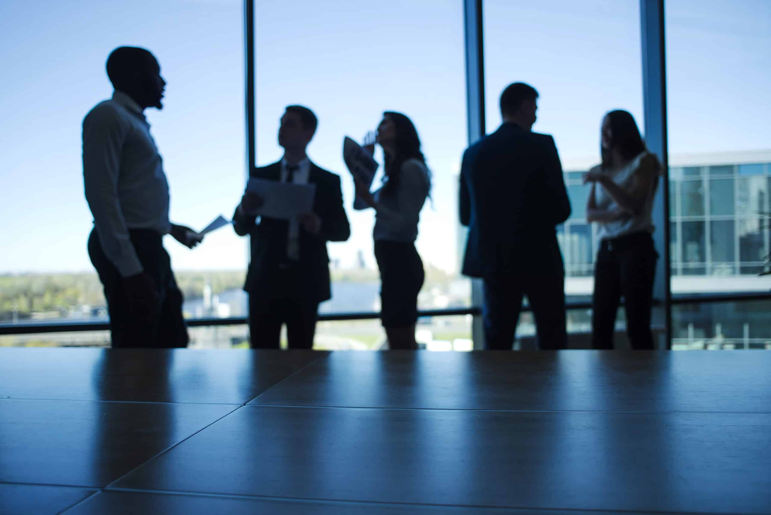 employer branding: profili di persone che chiacchierano in ufficio davanti a una vetrata