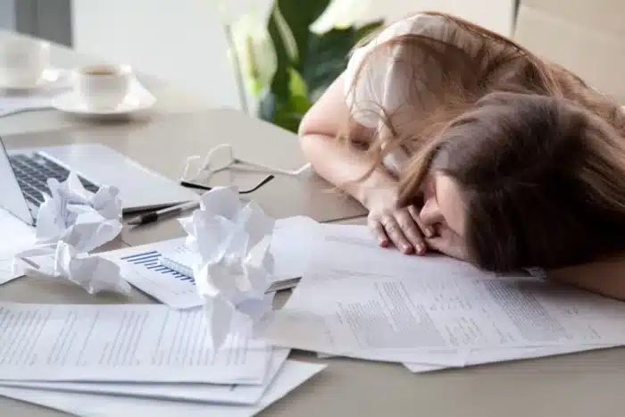 lavoratrice stanca che riposa sulla scrivania ingombra di carte